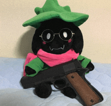 a stuffed animal wearing a green hat and scarf holds a gun