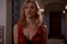 a woman in a red bra is standing in a hallway looking at the camera .