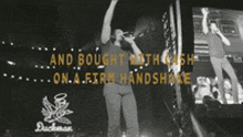 a man singing into a microphone on a stage with the words and bought with cash on a firm handshake