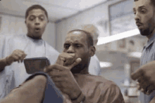 a man is getting his hair cut at a barber shop and looking at his phone