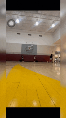 a basketball game is being played in a gym with a yellow and white court