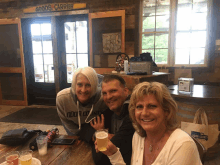 three people sitting at a table with a sign that says goods carrier