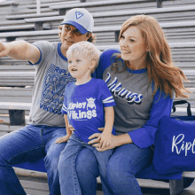 a man and woman are sitting on a bench with a little boy wearing a shirt that says ripley vikings