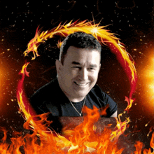 a man in a black shirt is smiling in front of a fire circle