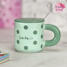 a green polka dot mug with the words smile written on it