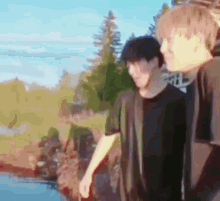 two men are standing next to each other in front of a body of water