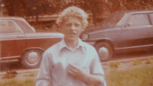 a man in a white shirt is standing in front of a red car