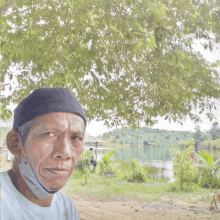 a man wearing a face mask stands under a tree