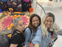 three women are posing for a picture in front of a display of day of the dead items