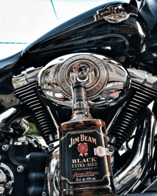 a bottle of jim beam sits on top of a motorcycle