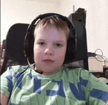 a young boy wearing headphones and a microphone while sitting in a chair .