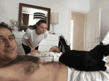 a man laying on a bed next to a woman and a cat