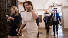 a woman in a white dress is talking on a phone