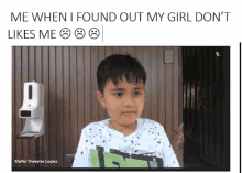 a young boy is sitting in front of a hand sanitizer dispenser and making a funny face