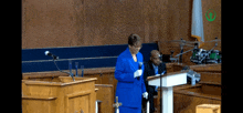 a woman in a blue suit stands at a podium