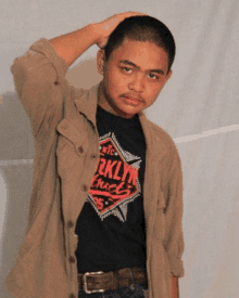 a man wearing a brooklyn truck shirt holds his head