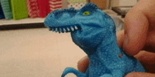 a person is holding a blue toy dinosaur in their hands