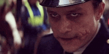 a close up of a man in a police uniform with a joker face paint .