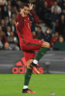 a soccer player with the number 1 on his jersey stands on one leg