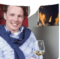 a man in a striped shirt is smiling while holding a glass of white wine