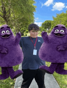 a young man is standing next to two purple mascots .