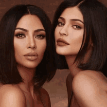 kim kardashian and kylie jenner are standing next to each other and posing for a picture .