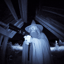 a man in a wizard costume holds a gun in his hand