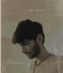 a man with a beard is looking down in a sepia tone photo