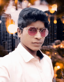 a young man wearing sunglasses and a white shirt poses for a photo