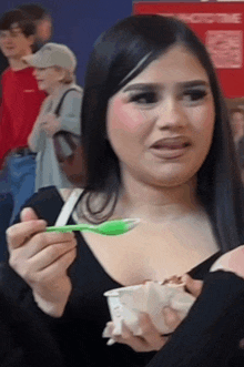 a woman is holding a green spoon in her hand