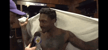 a shirtless man is being interviewed in a locker room by a man wearing a purple hat