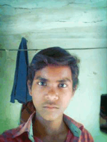 a young boy taking a selfie with a blue towel hanging on a clothes line behind him