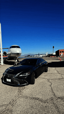 a black lexus is parked in front of a private jet with a california tag