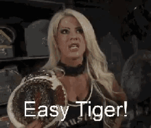 a female wrestler is holding a wrestling championship belt and saying `` easy tiger '' .