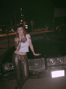 a woman smoking a cigarette while standing next to a black car with a license plate that says california