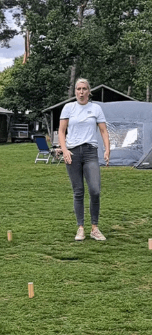 a woman is standing on a lush green field in front of a tent and a tent .