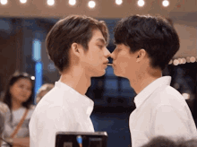 two young men are kissing each other while one of them is eating a candy bar .