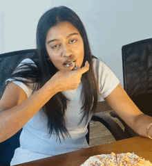 a woman is sitting at a table eating a slice of pizza