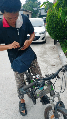 a man is standing next to a bicycle and looking at a cell phone