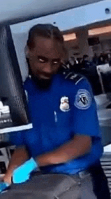 a man in a blue uniform and blue gloves is standing next to a table .