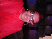 a woman wearing glasses and hoop earrings is smiling for the camera