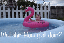 a little girl is in a pool with a pink flamingo float