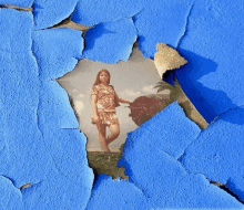 a girl in a dress is standing in a field behind a blue wall