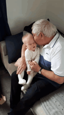 a man kisses a baby on the cheek while sitting on a couch