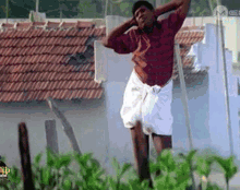 a man in a red shirt and white shorts is jumping in the air in front of a building .