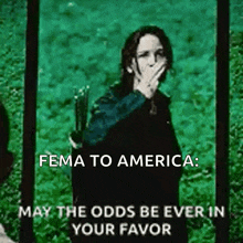 a woman covering her mouth with her hand and the words fema to america may the odds be ever in your favor below her