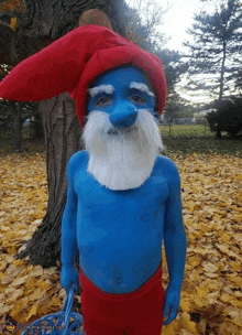 a child dressed in a smurf costume stands in a pile of leaves