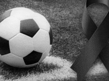 a black and white photo of a soccer ball and a black ribbon on a field