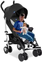 a man in a blue shirt is sitting in a chicco stroller holding a doll