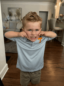 a young boy wearing a striped shirt with the letter t on it making a funny face